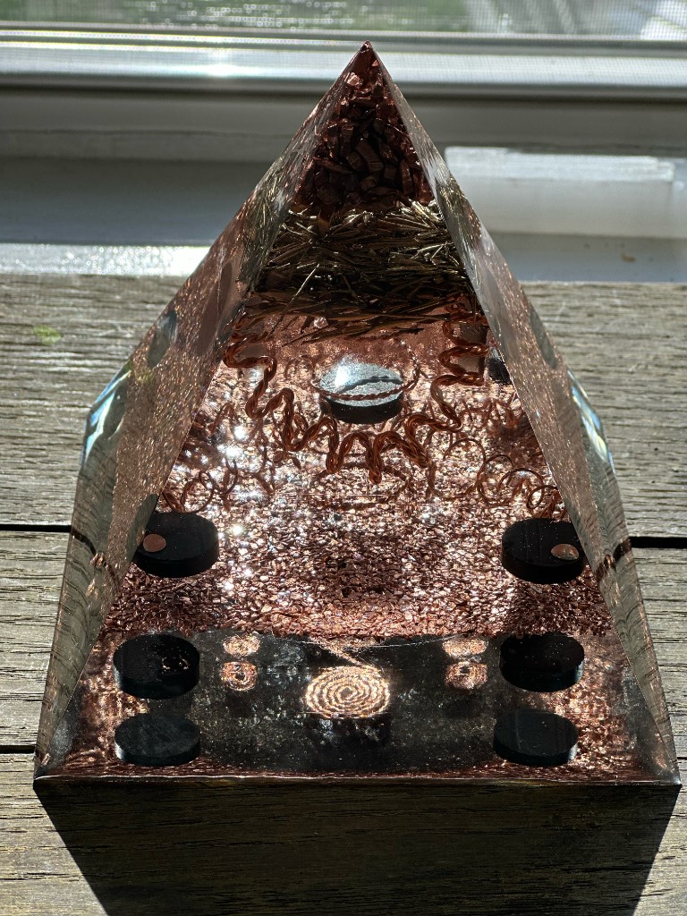 Handmade large orgonite pyramid with copper, shungite, and brass on wooden deck, crafted by The Northern Daisy in Maine
