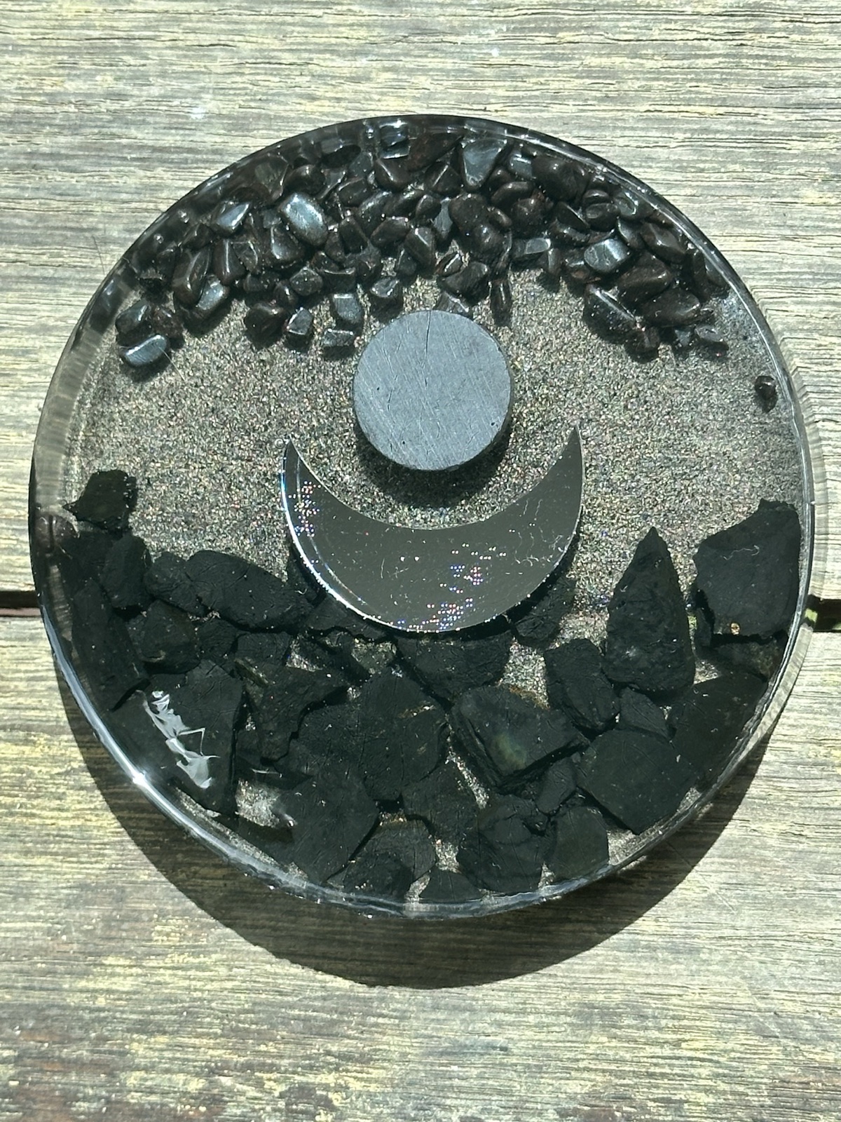 Single crescent moon in copper on dark resin with shungite, hematite, and iron filings.