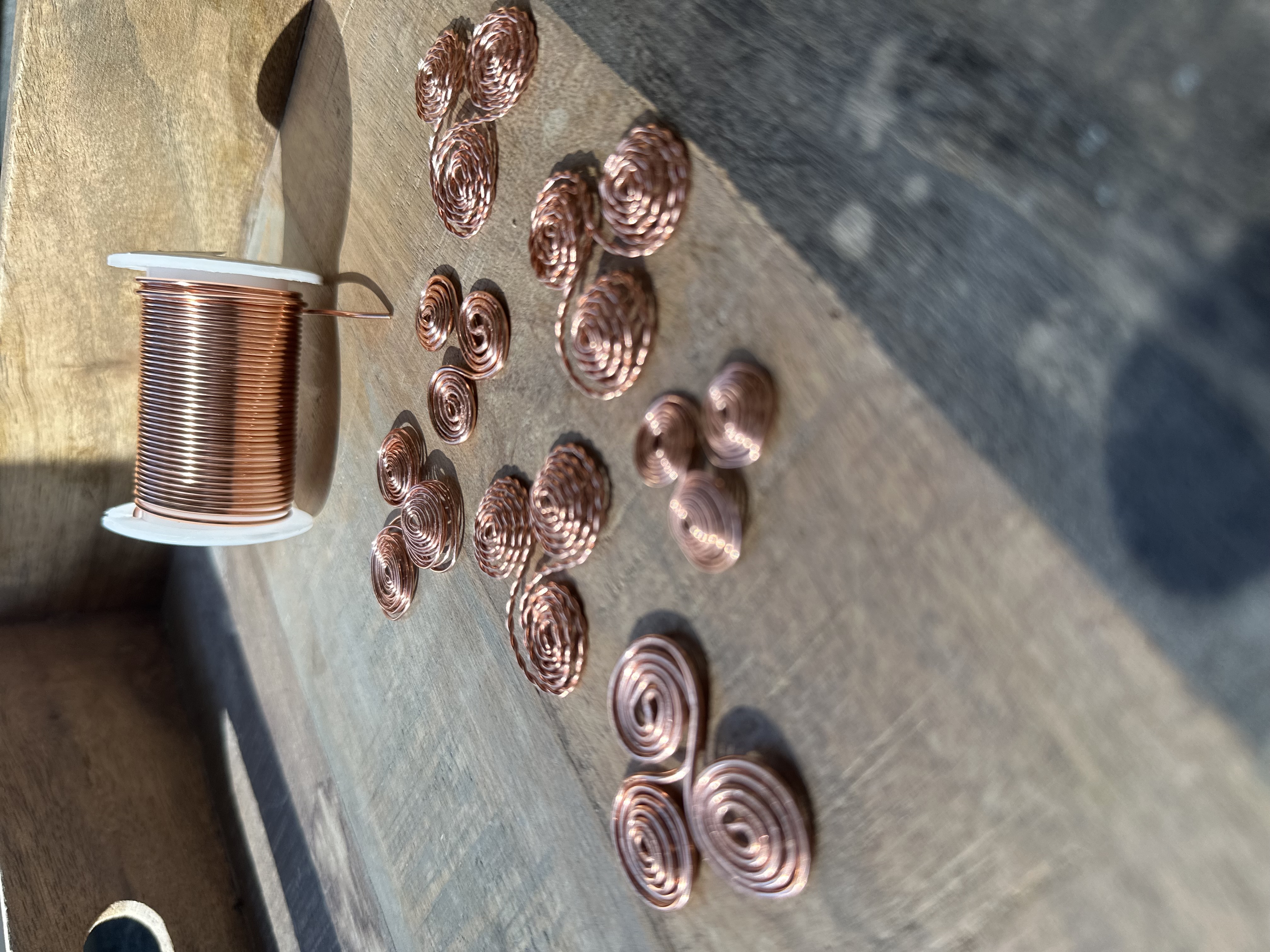 Copper wire triskelion viewed from overhead, showing triple spiral geometry