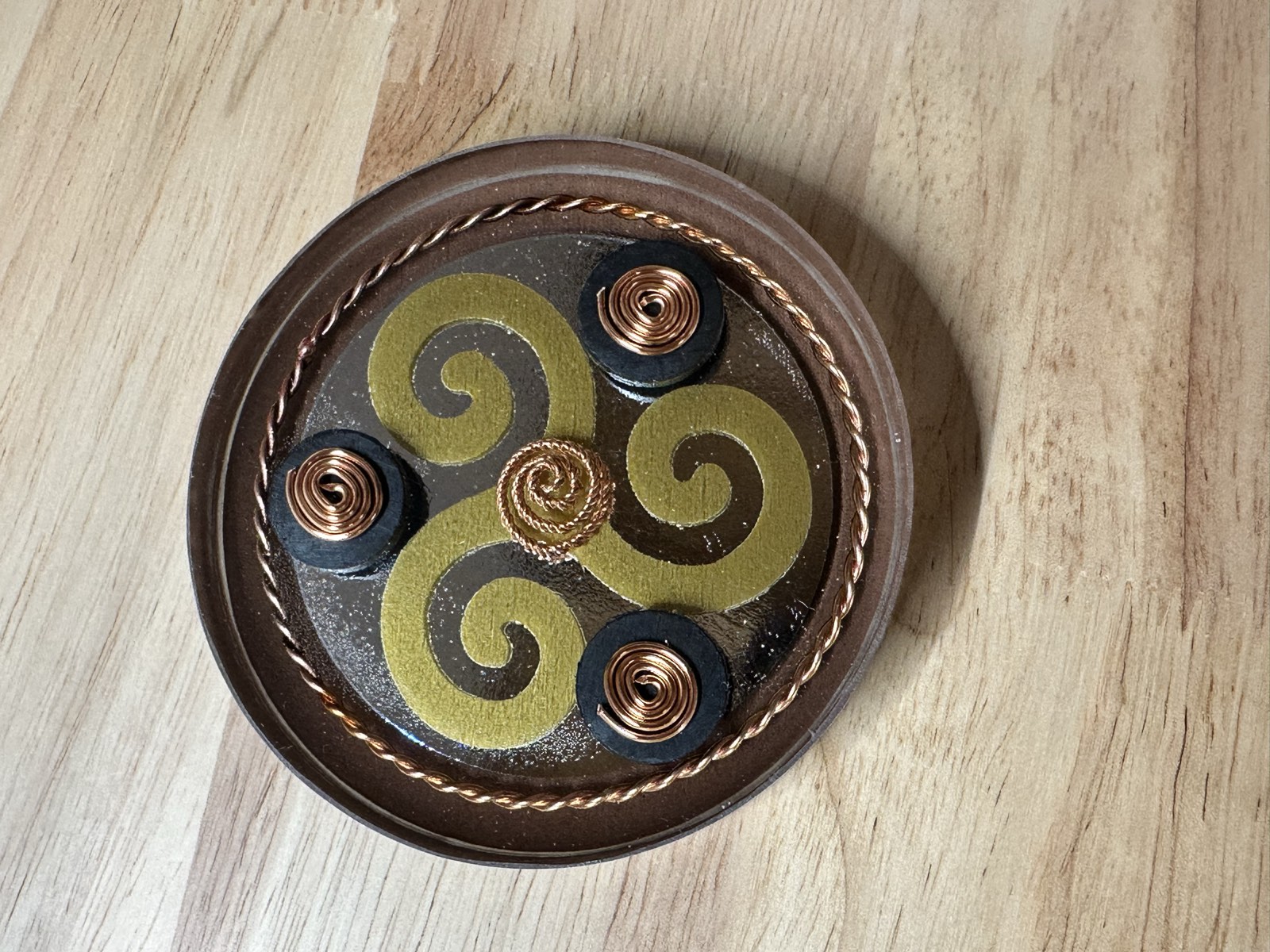 Yellow triple spiral on mirrored black resin with copper tensor ring, three black magnets, and brass center.