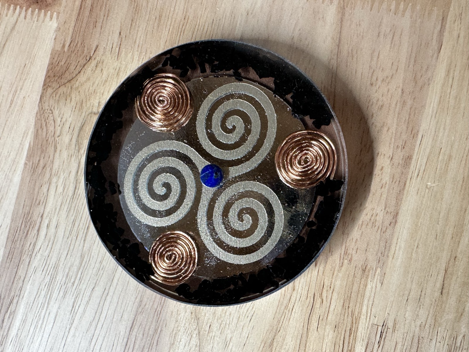 Silver triple spiral on mirrored black resin with four copper compass spirals and a lapis center.